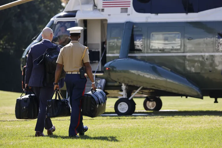 President Joe Biden astumas helikopterisse. Temaga on kaasas USA mereväeohvitser, kelle näpus olev komps pole muud kui nn tuumajalgpall ehk tuumakohver.