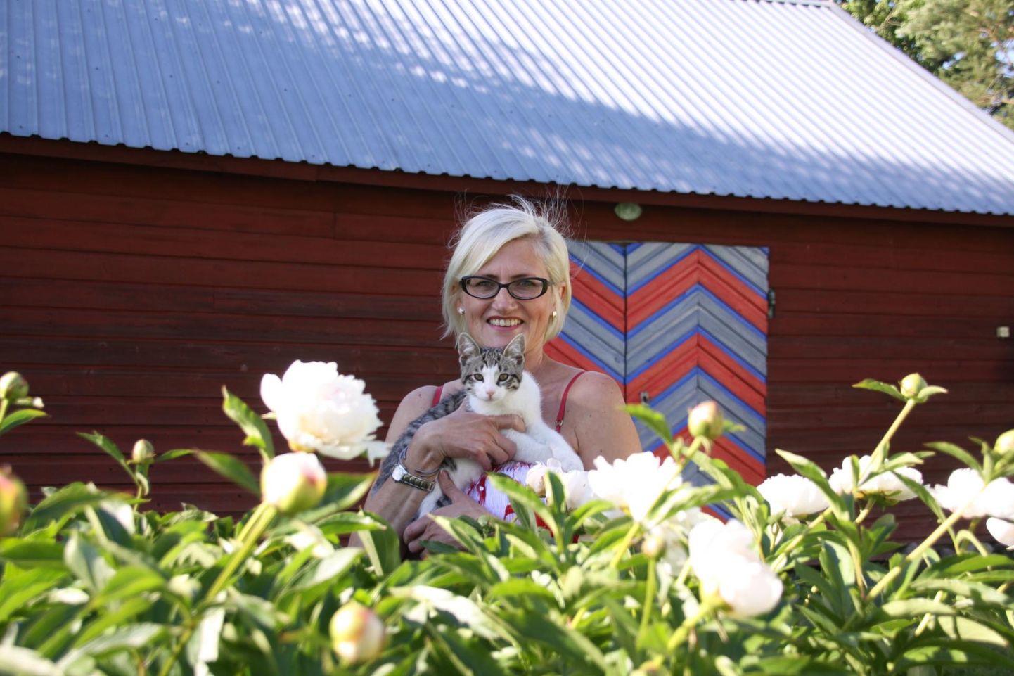 Uue-Kulli talu perenaine Annela Ojaste koondas pildile oma lemmikud: kass Oskari, põlvest põlve hoitud pojengipõõsa ja kevadel Paide kihelkonna värvidesse võõbatud ukse.