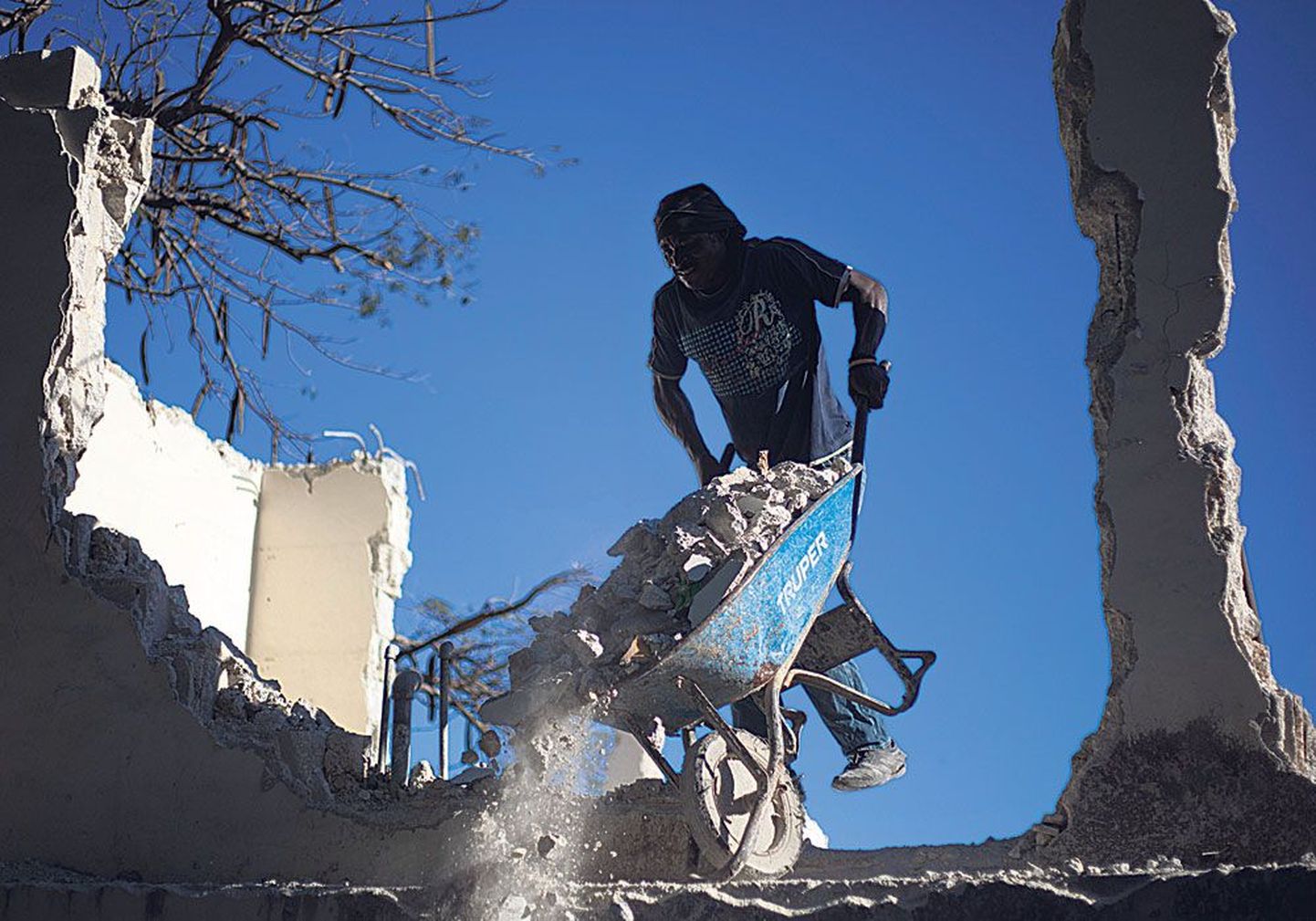 Местный житель в прошлую пятницу в Песьон-Виле, предместье гаитянской столицы Порт-о-Пренса, на уборке обломков школы, пострадавшей во время землетрясения три года назад. К настоящему моменту большая часть обломков убрана с улиц.