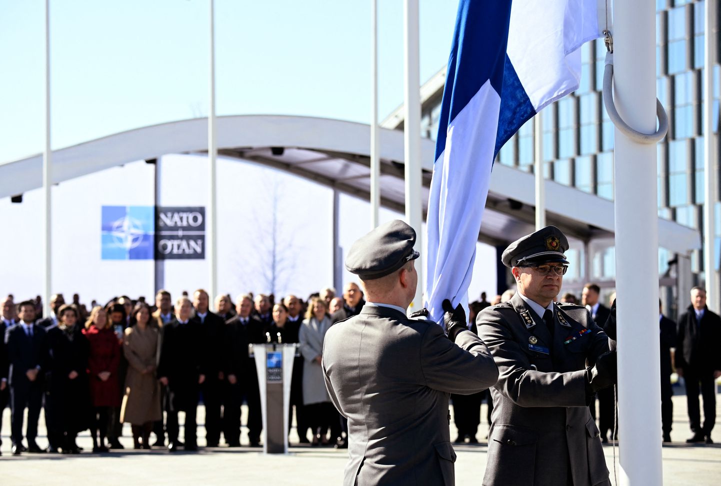 Финские военнослужащие устанавливают национальный флаг Финляндии у штаб-квартиры НАТО в Брюсселе