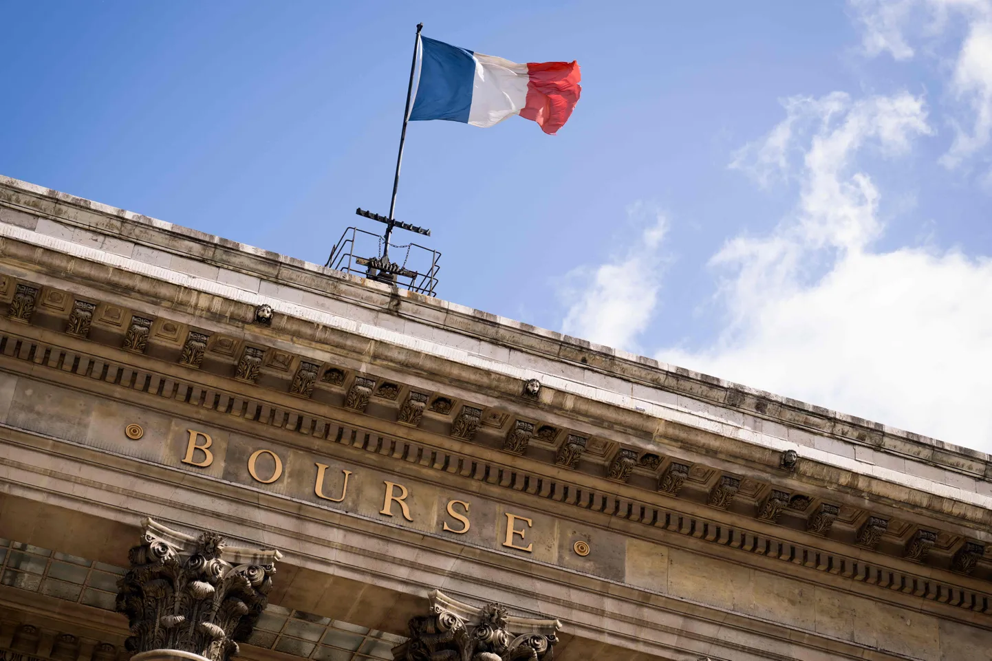 This photograph taken on April 21, 2024 shows the France national flag flying over the former headquarters of the French Stock Exchange, Bourse de Paris or Palais Brongniart in Paris. (Photo by MIGUEL MEDINA / AFP)