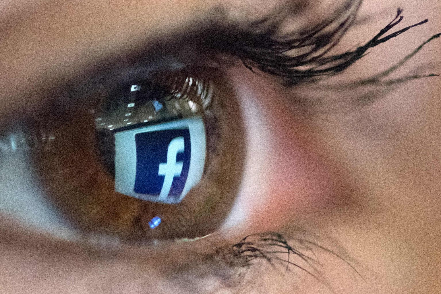 Facebooki logo peegeldumas naise silmas. Pilt on illustreeiv