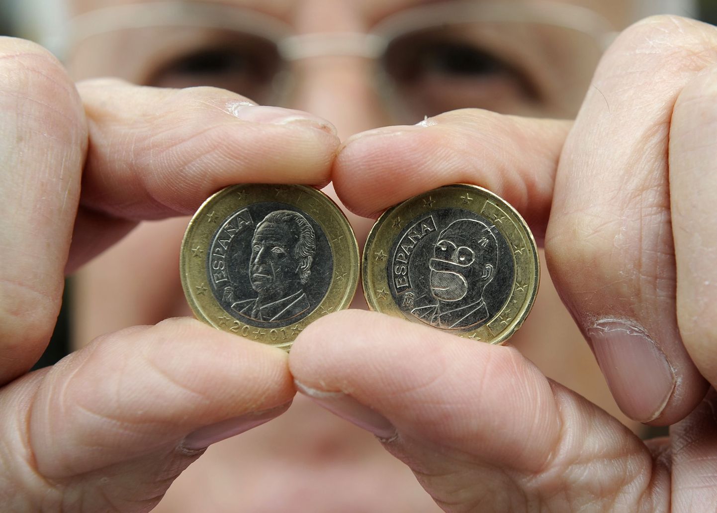 Hispaania poeomanik Jose Martinez näitamas kuningas Juan Carlose kujutiseg ühe euro suurust münti (vasakul) ja võltsitud ühe eurost münti, millel on kujutatud Homer Simpson (paremal)