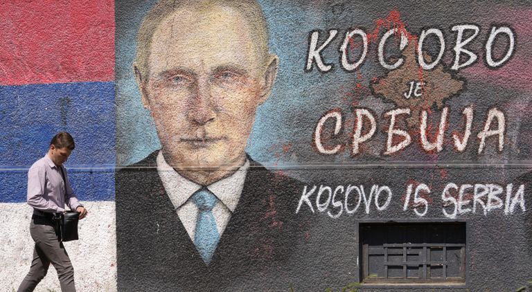 A man walks past a graffiti on a wall depicting the Russian President Vladimir Putin and Serbian flag in Belgrade, Serbia, Friday, May 13, 2022. The Cyrillic letters on graffiti read "Kosovo is Serbia". Serbia has joined condemnation at the United Nations of the Russian attack, but has refused to impose sanctions against Moscow — despite formally seeking to join the European Union. Pro-Russian sentiment and support for the invasion remain high in Serbia. (AP Photo/Darko Vojinovic)