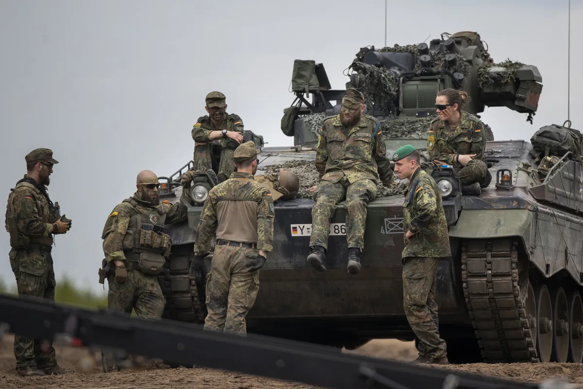 German Bundeswehr soldiers of the NATO enhanced forward presence battalion wait to greet German Chancellor Olaf Scholz ahead of his arrival at the Training Range in Pabrade.