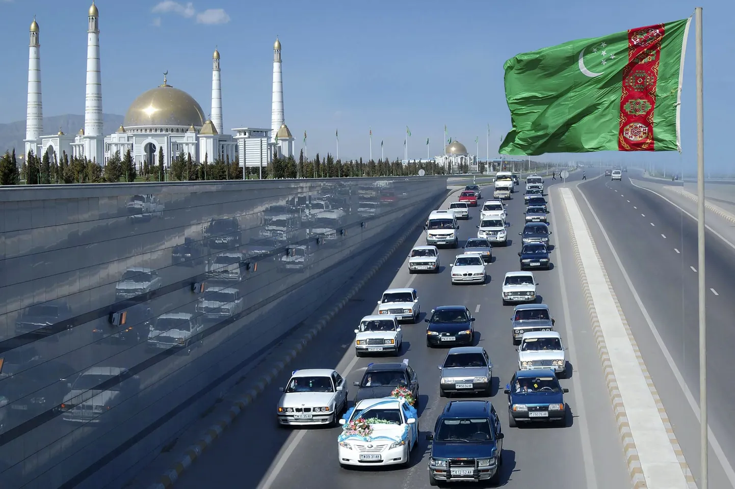 Türkmenistani lipp automagistraali ääres pealinnas Aşgabatis. Eemalt paistab ekspresidendi Saparmurat Nijazovi mausoleum.