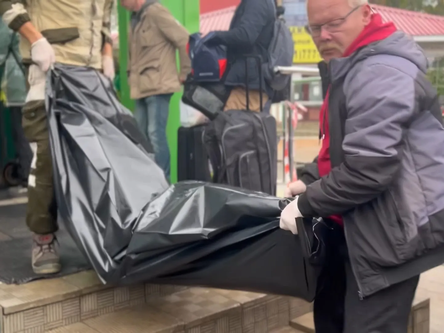 Труп в черном полиэтиленовом пакете выносят из пограничного пункта на границе России с Эстонией, 11 октября 2024 года.