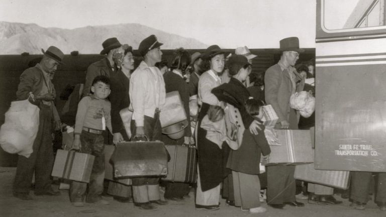 Американцы японского происхождения пересаживаются с поезда на автобус в Лоун-Пайн, Калифорния. 1942 год