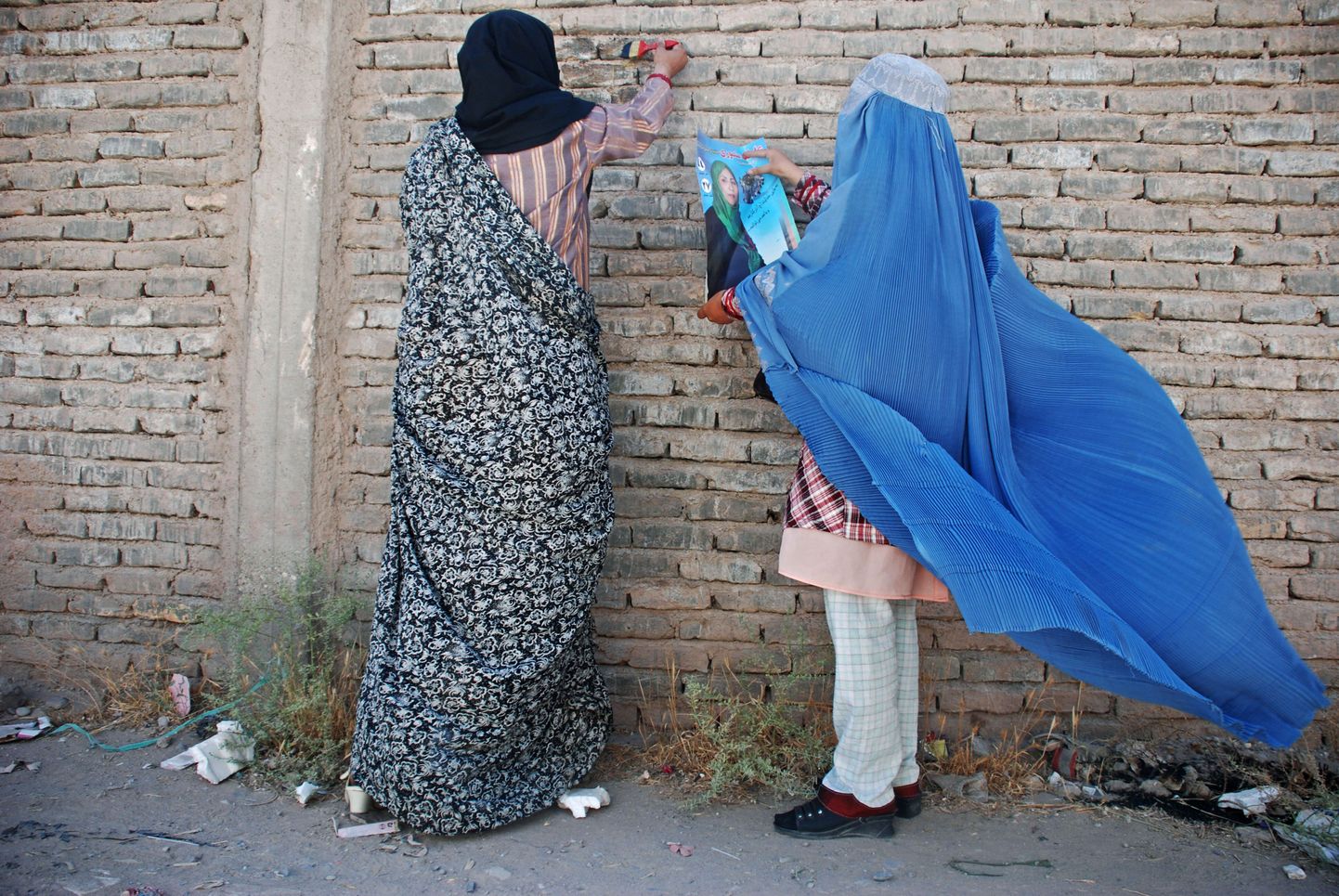 Afgaani naised kleepimas seinale parlamenti pürgiva poliitiku plakatit.
