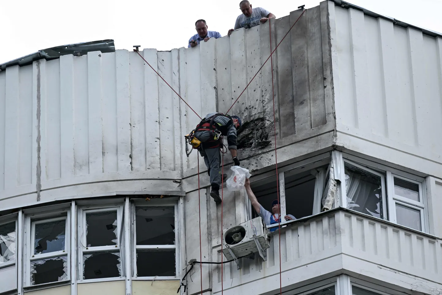 Специалист осматривает поврежденный фасад многоэтажного жилого дома после сообщения об атаке беспилотника в Москве 30 мая 2023 года.