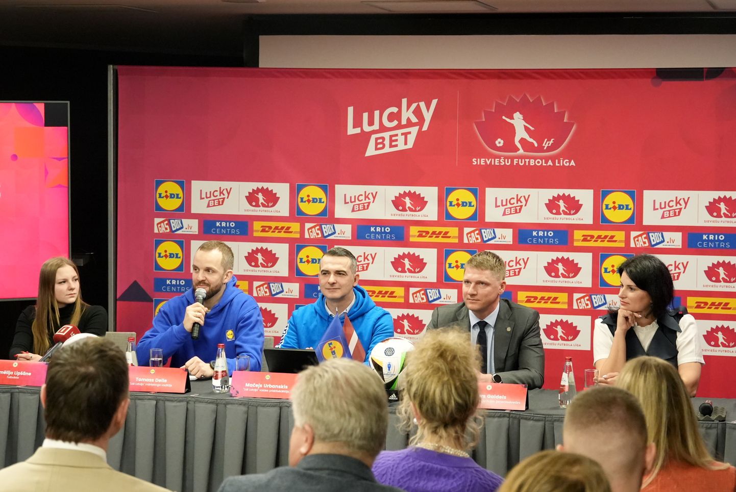 Futboliste Amēlija Lipšāne (no kreisās), "Lidl Latvija" mārketinga vadītājs Tomass Delle, "Lidl Latvija" valdes priekšsēdētājs Mačejs Urbanskis, Latvijas Futbola federācijas (LFF) ģenerālsekretārs Arturs Gaidels un LFF valdes locekle Anastasija Kučinska piedalās preses konferencē