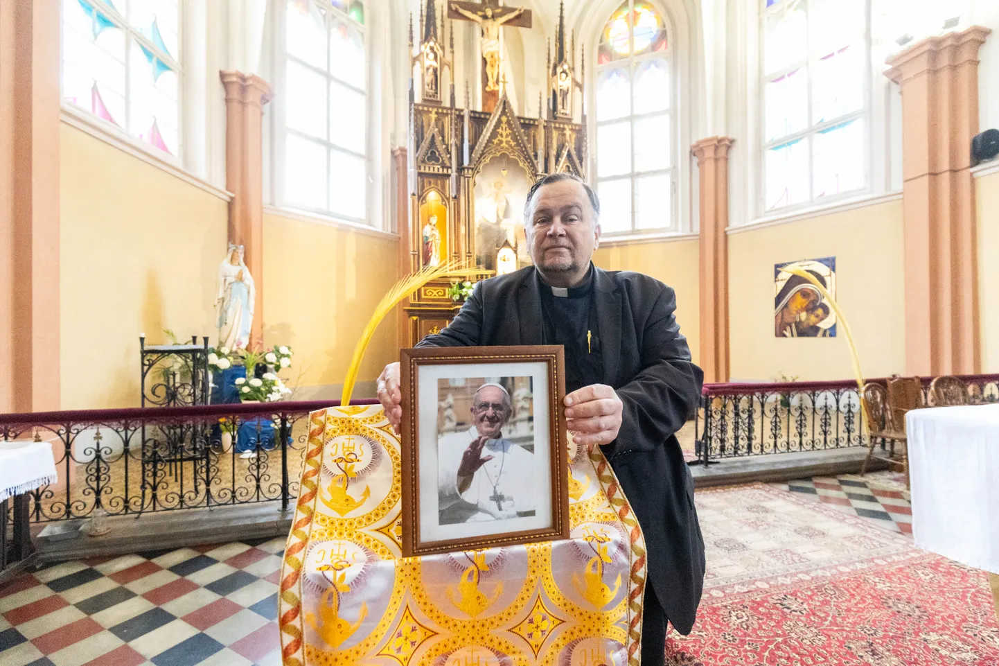 Isa Miguel sätib Tartu katoliku kirikus paavst Franciscuse fotot, mis on leina märgiks asetatud altari lähedale.