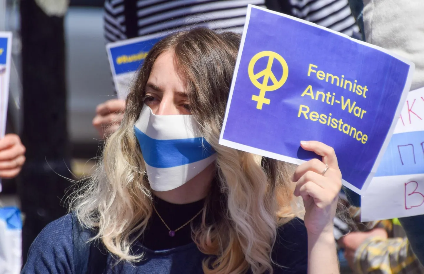 Meeleavaldaja kannab aprillis Londonis Venemaa saatkonna juures näol valgesinivalget värvikombinatsiooni, mis on saanud Vene sõjavastaste sümboliks, ning käes silti, mis viitab feministide sõjavastasele vastupanule.