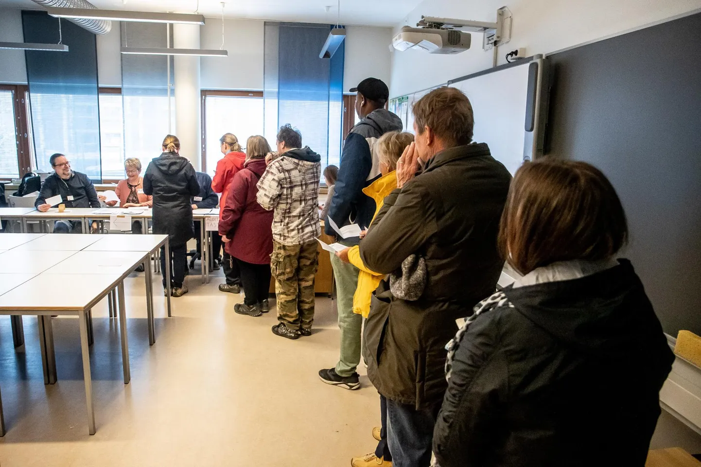 Hääletajad ootamas oma järjekorda koolimajas avatud valimisjaoskonnas Espoos. Nii mõningi selles reas seisnu pidi veel suunduma teisegi järjekorda, sest samas koolimajas olid ühe koridori peal kolme piirkonna jaoskonnad, kuid enamik inimesi pööras algatuseks sisse esimesest avatud klassiuksest. FOTO:SANDER ILVEST/POSTIMEES FOTO: Sander Ilvest