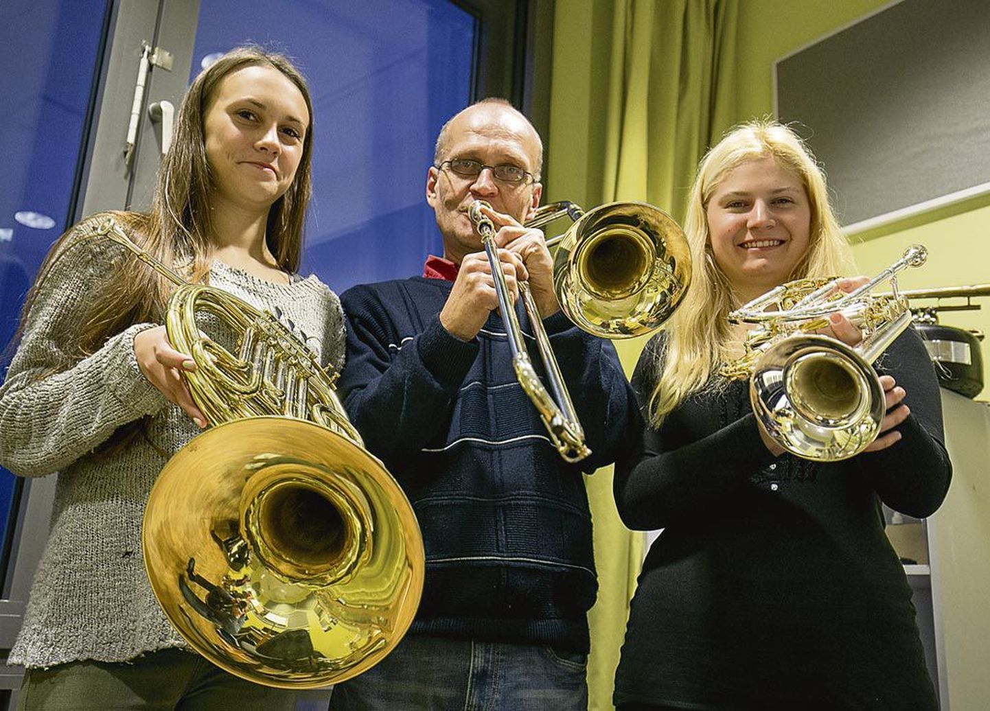 Õpilane Carina Aasa, õpetaja Arvi Sommer ja kontsertmeister Jaana Vetšerkovskaja näitavad uusi nn üleminekupille: metsasarve, trombooni ja kornetit.
