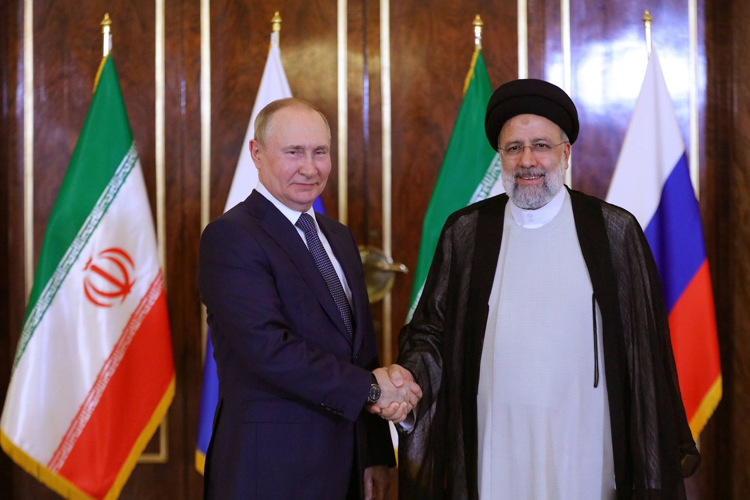 Президент Ирана Эбрагим Раиси (справа) обменивается рукопожатием с президентом России Владимиром Путиным.