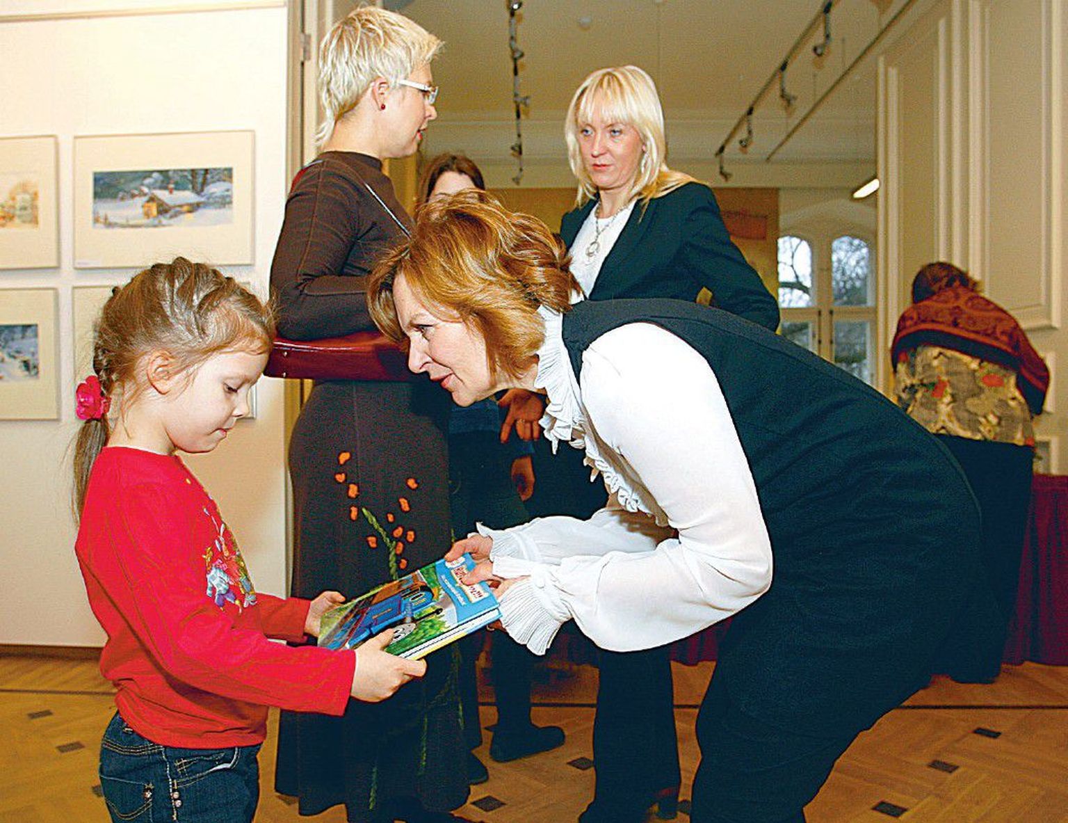 Kultuurivedur Anne Rande näitab pisikesele Kadri-Keiule raamatut vedurist, tagaplaanil tüdruku ema, presidendi abikaasa Evelin Ilves lobisemas Postimehe peatoimetaja Merit Kopliga.