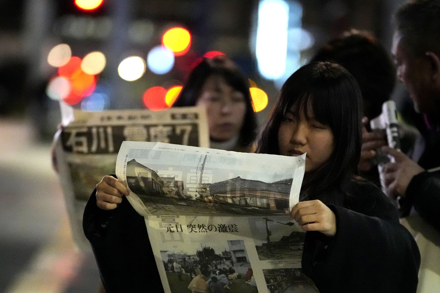 Jaapanlannad lugemas 1. jaanuaril 2024 Yomiuri Shimbuni erinumbrist uudiseid maavärinate kohta.