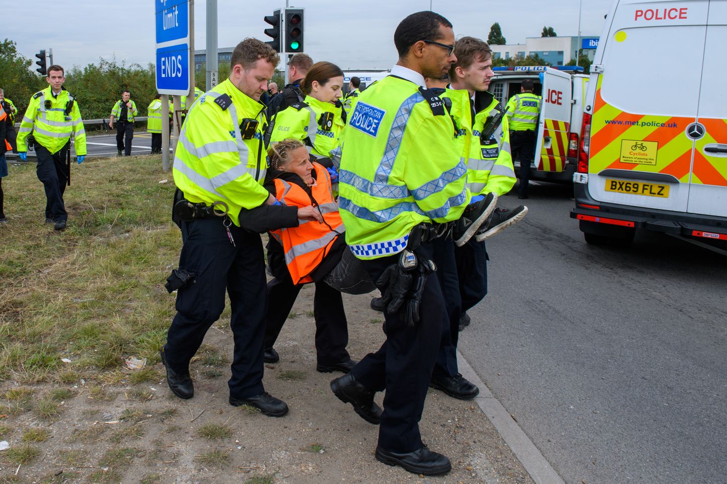 Briti politseinikud kliimaprotestijat kiirteelt minema toimetamas.