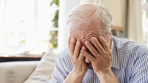 Senior Man Sitting On Sofa At Home Suffering From Depression Senior Man Sitting On Sofa At Home Suffering From Depression