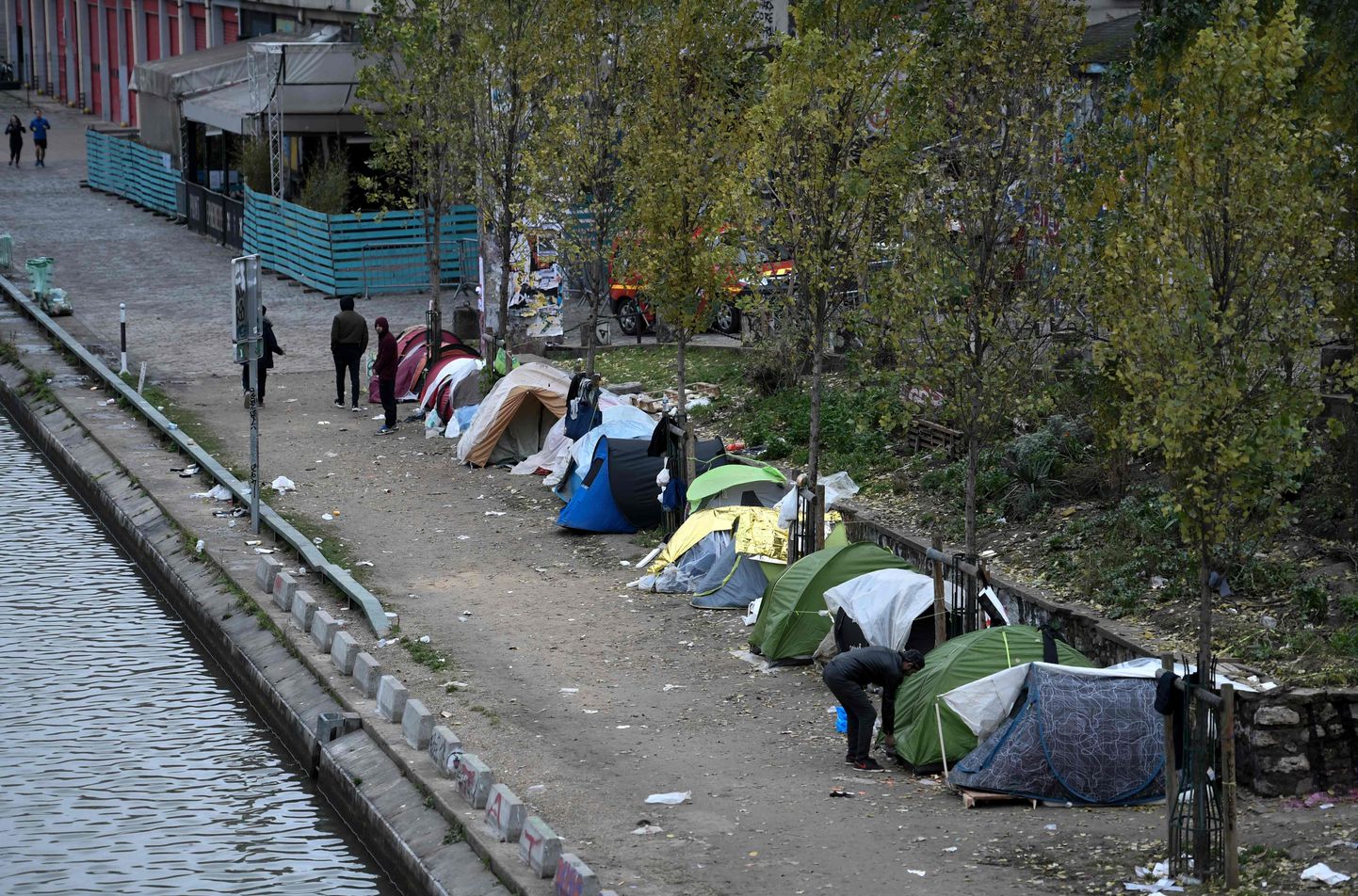 Meestegrupp seismas põgenike telkide kõrval Pariisis Saint-Martini kanali kallastel.