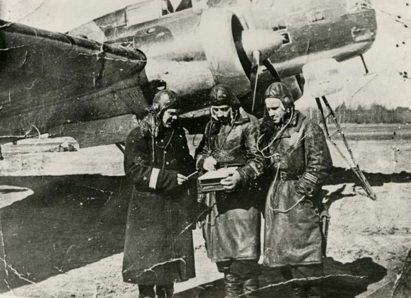 BERLIINI POMMITAMISEST osavõtnud laskurradist V. M. Krotenko 1942. a Novinki lennuväljal kaugpommitaja DB-3 taustal (paremal). Vasakul A. T. Drozdov, keskel N. D. 
Kotov.