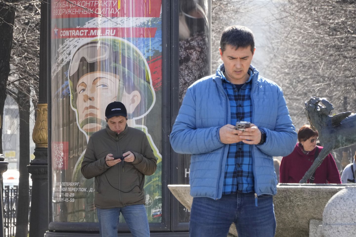 Mehed vaatamas Peterburis oma nutitelefone, taustaks sõjaväkke kutsumise plakat.