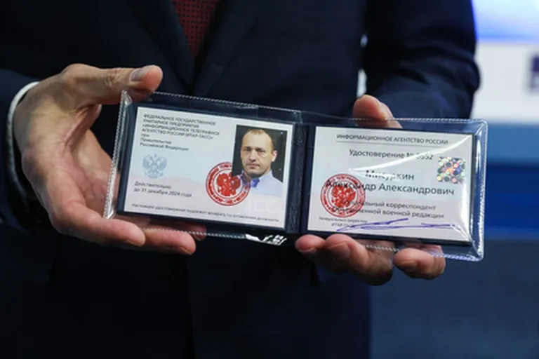 Venemaa kosmonautide treeningkeskuse asejuht Oleg Kononenko näitamas TASSi korrespondendi töötõendit, mis antakse kosmonaut Aleksandr Misurkinile