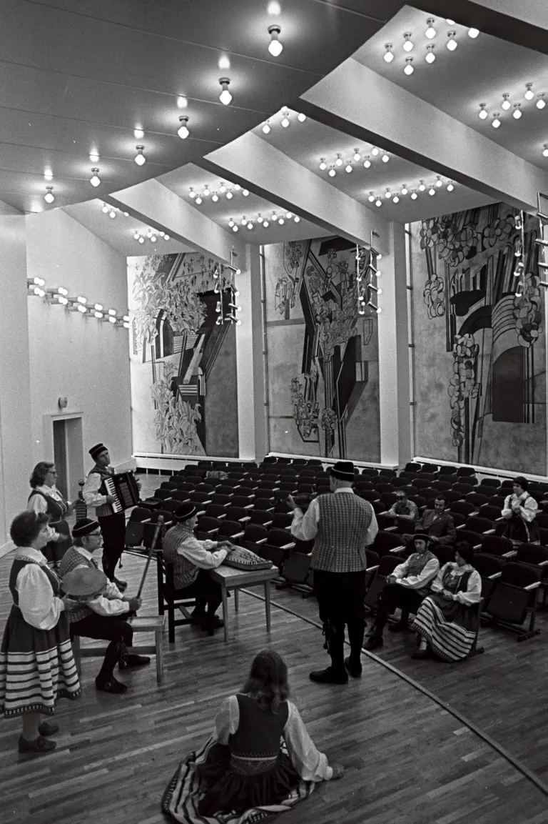 Põdrangu sovhoosi taidlejad klubisaalis harjutamas, taamal Eva Jänese sgrafiito. Foto: Endel Tarkpea, 1987.