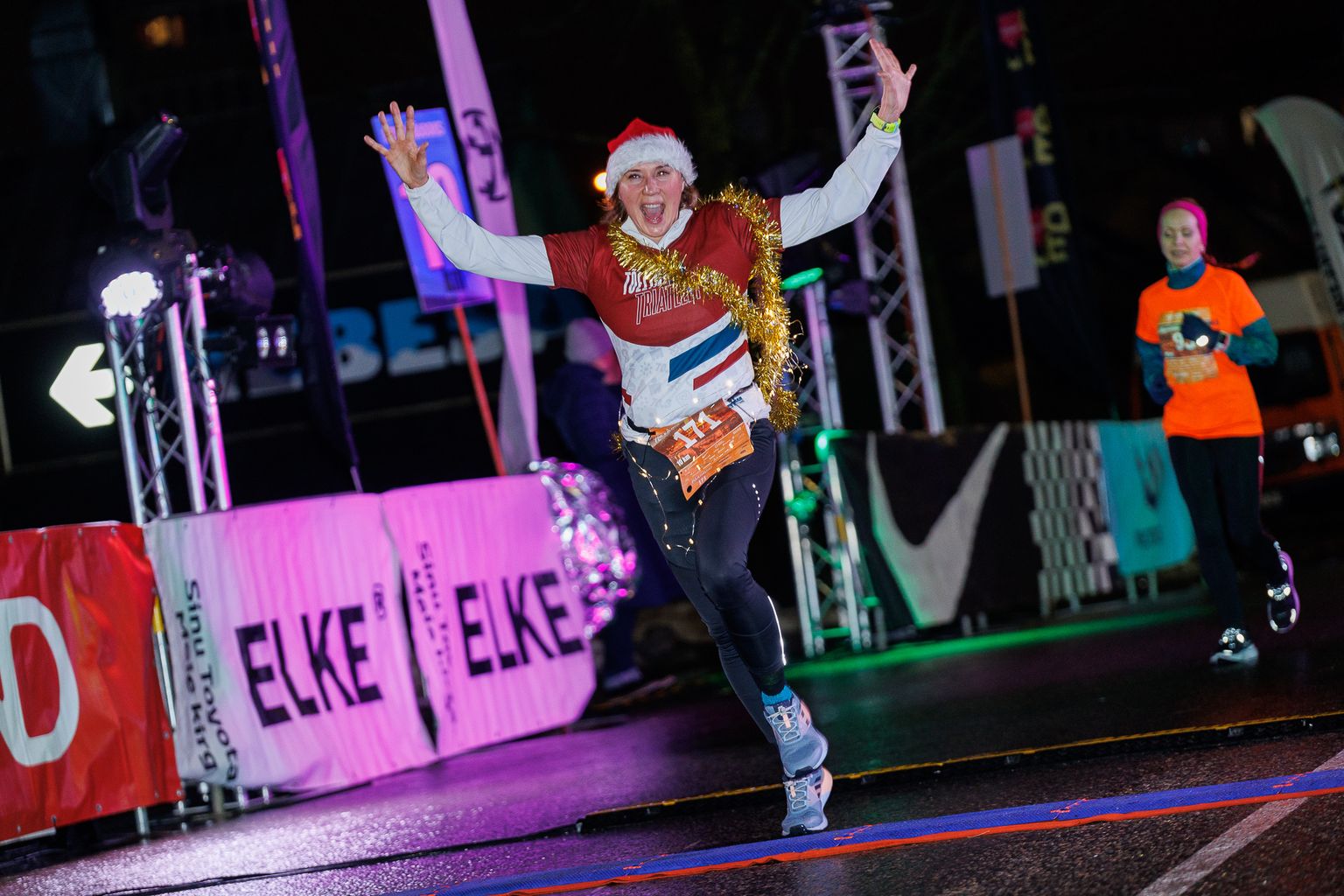 После десяти километров на трассе финишную черту пересекает ликующая Ирина Олейнич, которая пробежала дистанцию с рождественской гирляндой на шее.