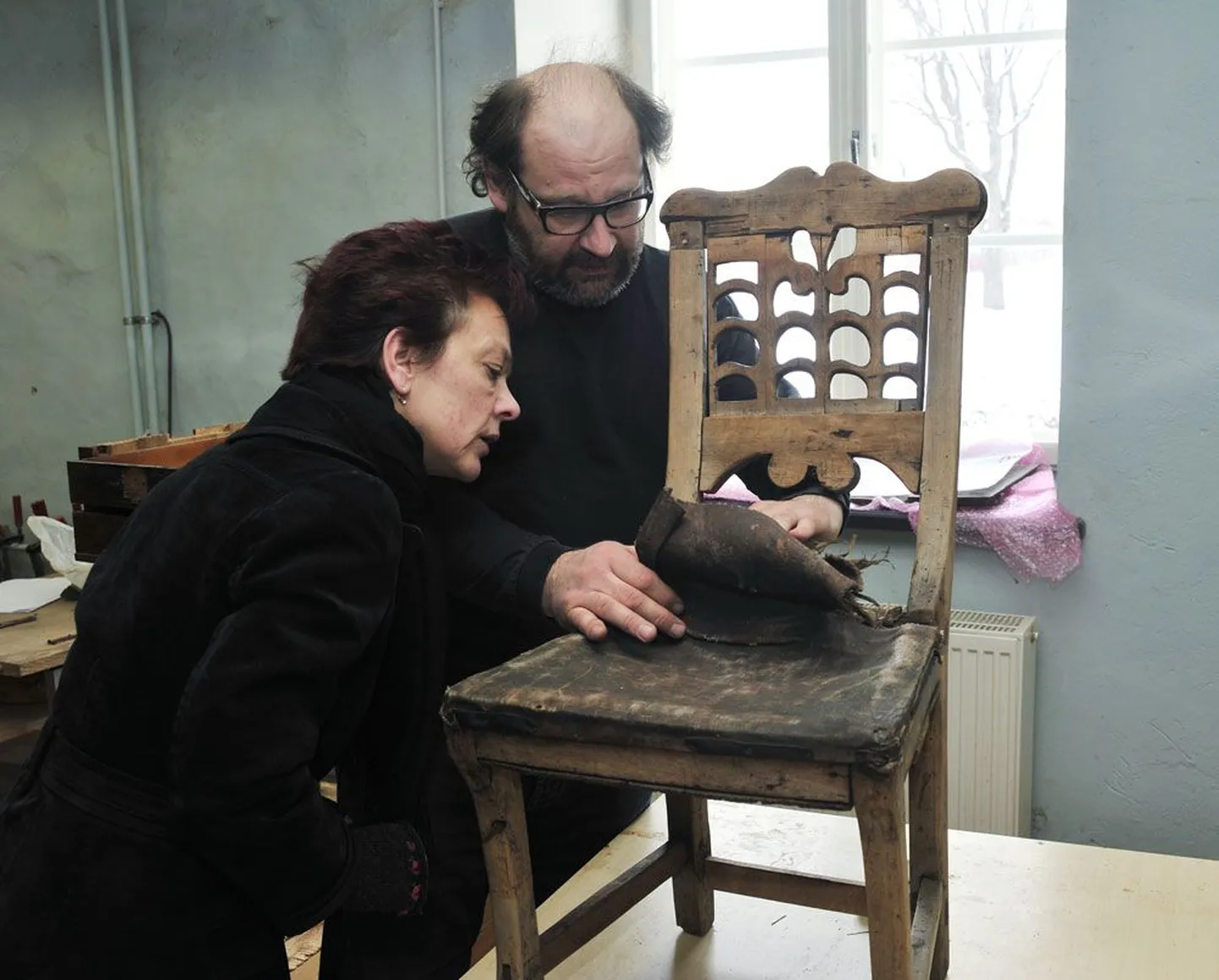 ERMi puidurestauraatorite osakonnas näitab konservaator Indrek Tirrul muuseumijuht Krista Arule haruldast ja vana Ruhnu tooli, mille polster tuleb ettevaatlikult lahti võtta, et tool väljapanekuks korda teha.