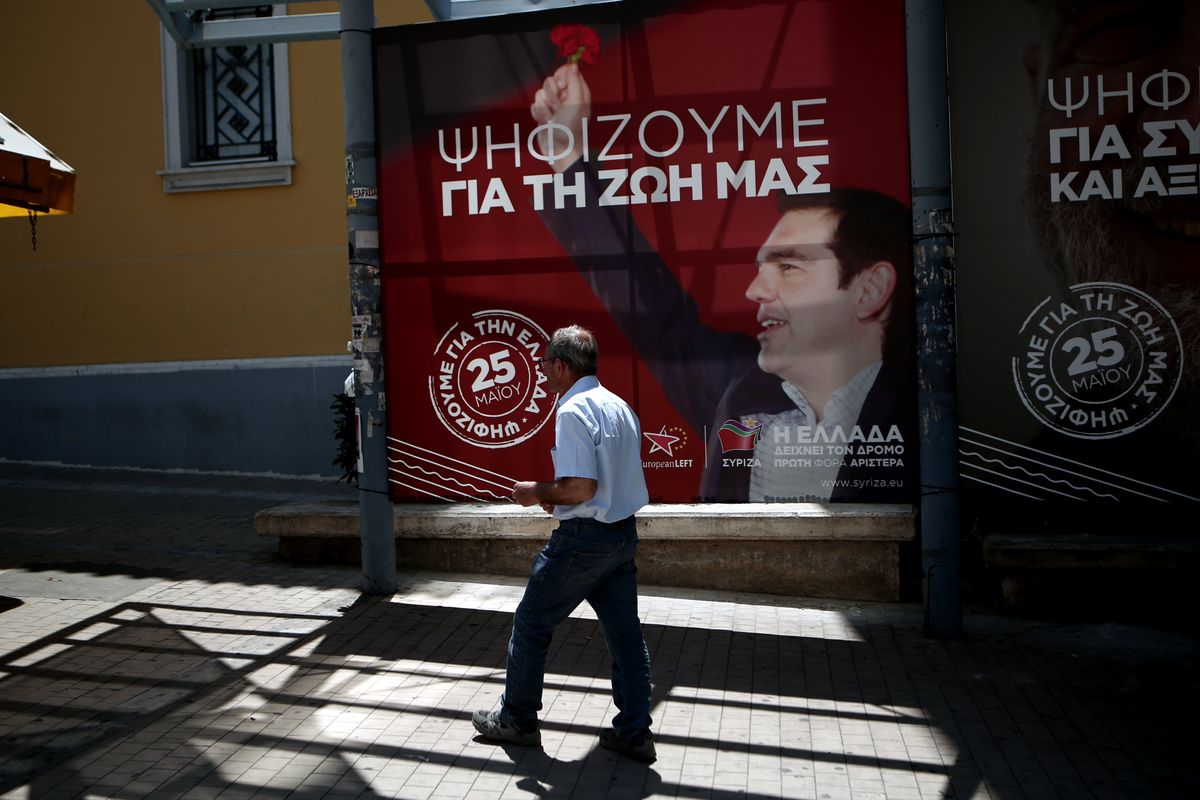 Мужчина проходит мимо плаката лидера левой оппозиции Алексиса Ципраса на улице Афин накануне евро выборов 2019 года.