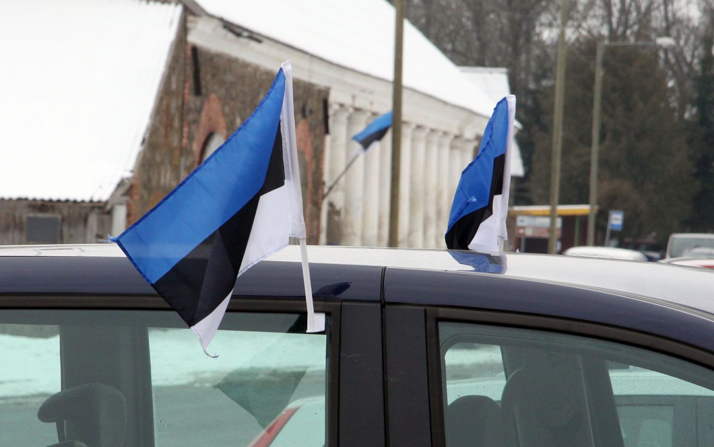 Auto külge kinnitatud Eesti rahvuslipud.