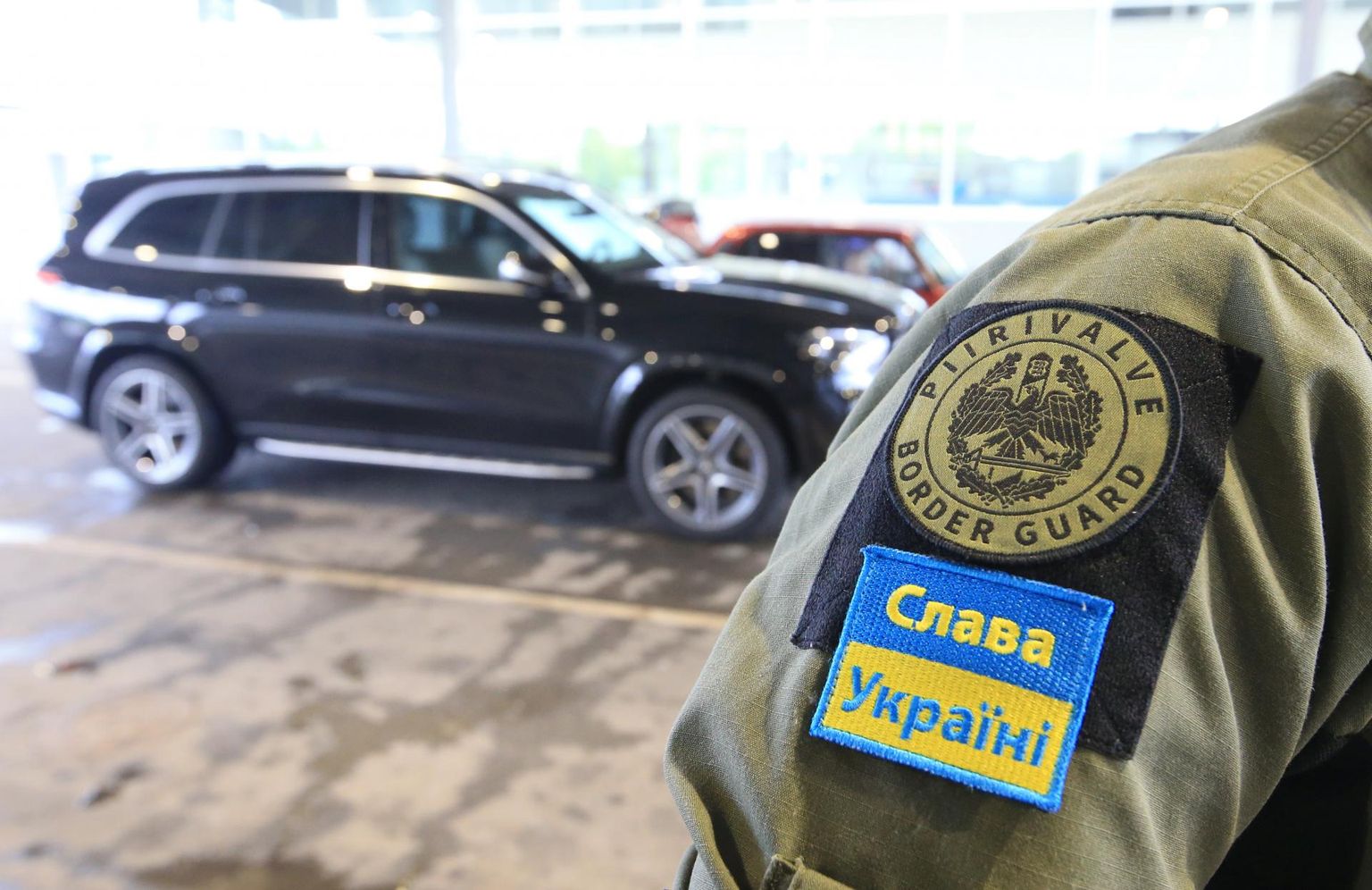 Robežpārejas punkts Luhamā. Igauņu robežsargam uz formastērpa lasāms uzraksts "Slava Ukrainai"