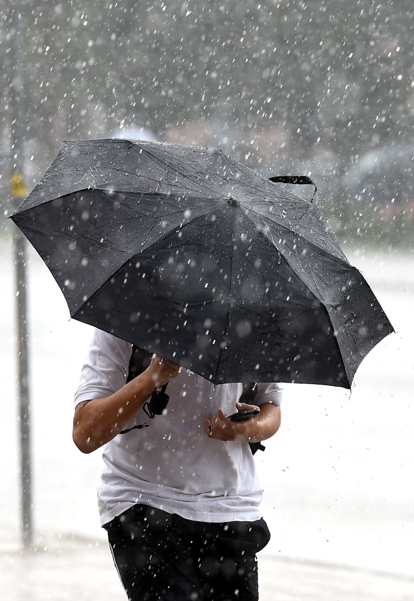 Jaunietis ar lietussargu lietus laikā. Ilustratīvs attēls.
