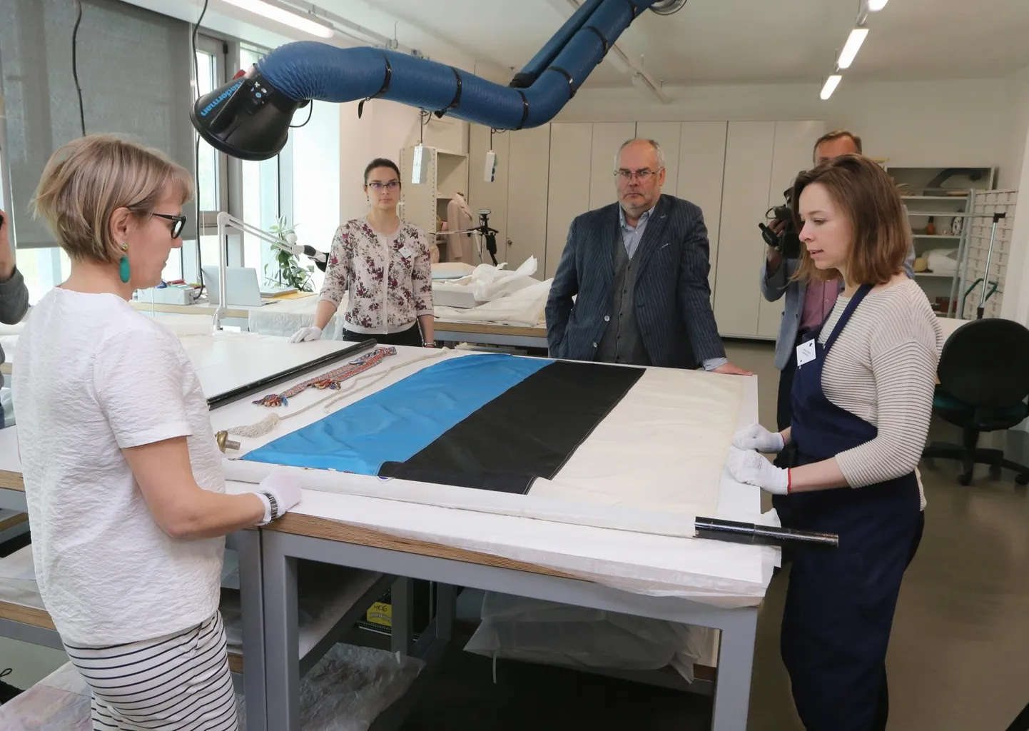ERMi direktoril Alar Karisel (tagaplaanil) seisab ees vastutusrikas ülesanne toimetada Esto päevade lipp 27. juuniks Helsingisse. Et plagu nagu kord ja kohus korras oleks, uurivad seda ERMi peavarahoidja Riina Reinvelt (ees vasakul) ja konserveerimisosakonna juhataja Kristiina Piirsild.