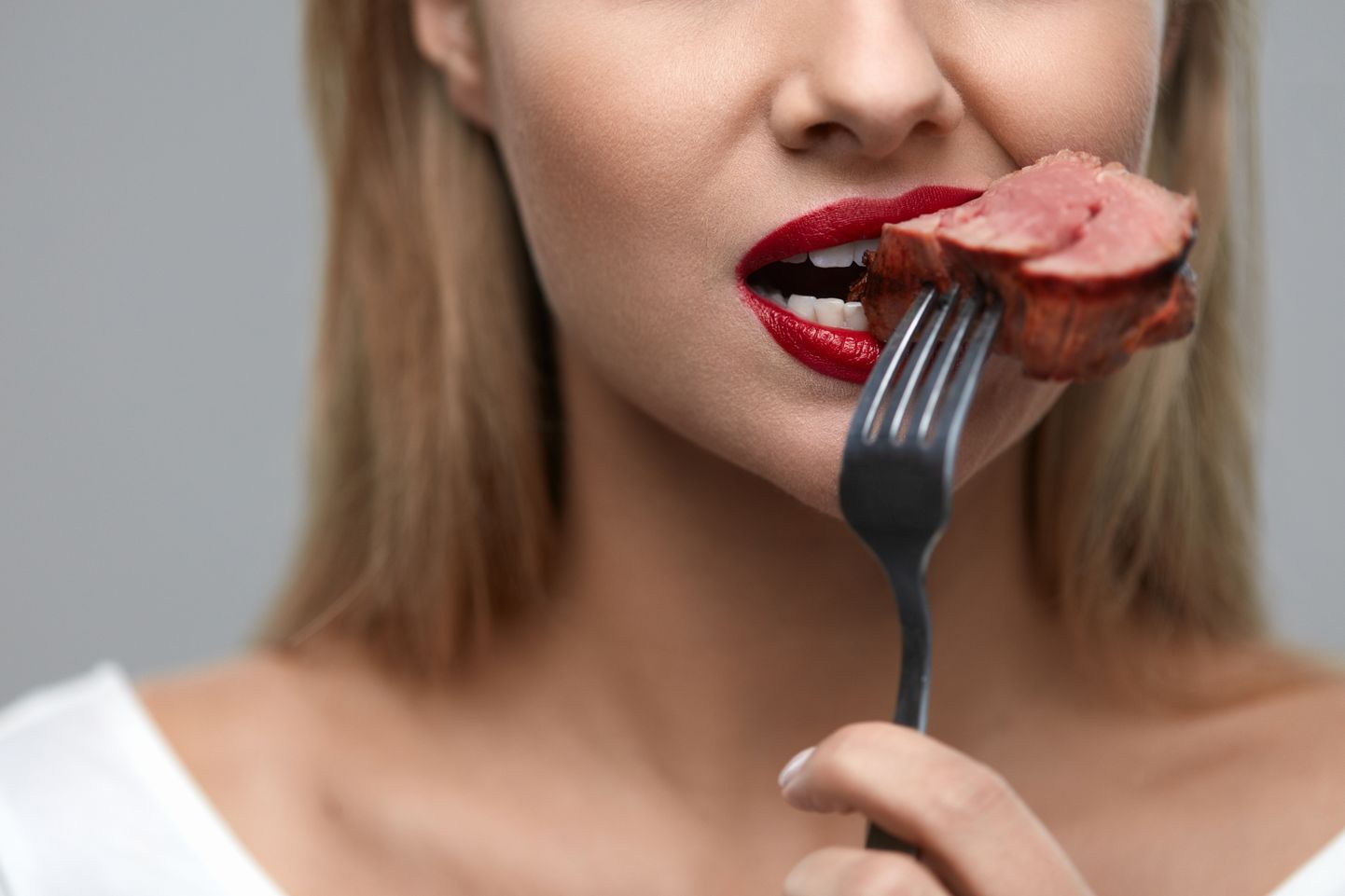 Женщина ест красное мясо. Иллюстративное фото.