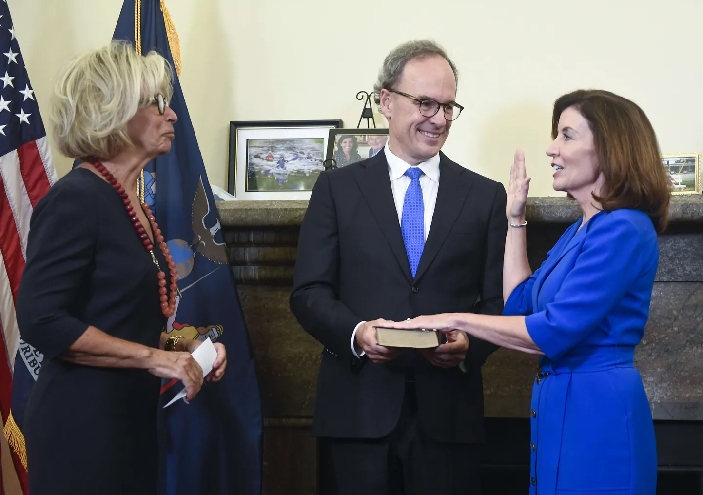 Kathy Hochul annab vannet, käsi piiblil, mida hoiab tema abikaasa Bill Hochul. Vasakul osariigi ülemkohtunik Janet DiFiore.