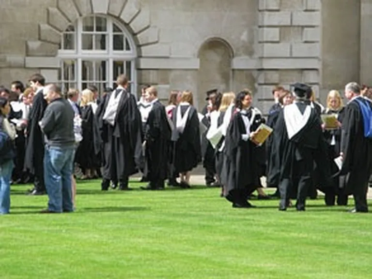 Kembridžas universitātes studenti tradicionālajos tērpos ar kapuci 