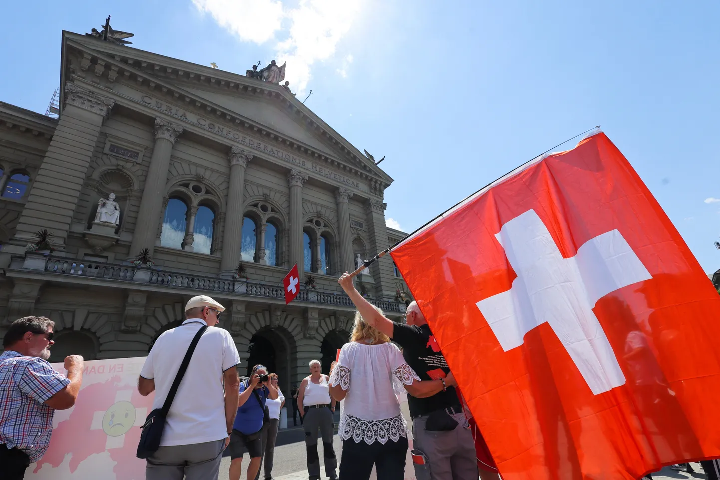 Šveitsi lippudega inimesed Bernis parlamendihoone ees. Pilt on illustreeriv.