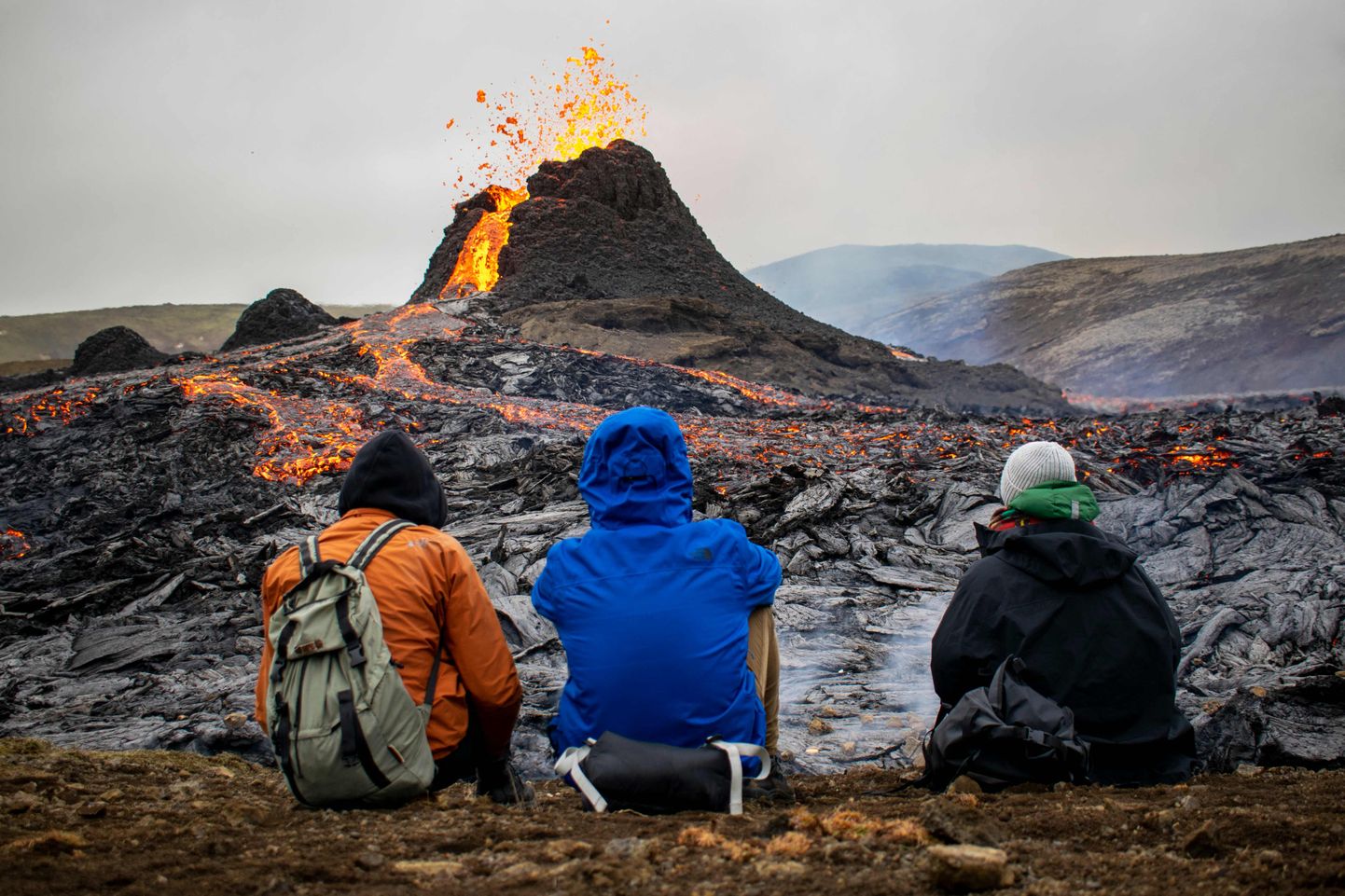 Туристы-походники наблюдают за извержением вулкана Фаградальсфьядль в Исландии, 21 марта 2021 года.