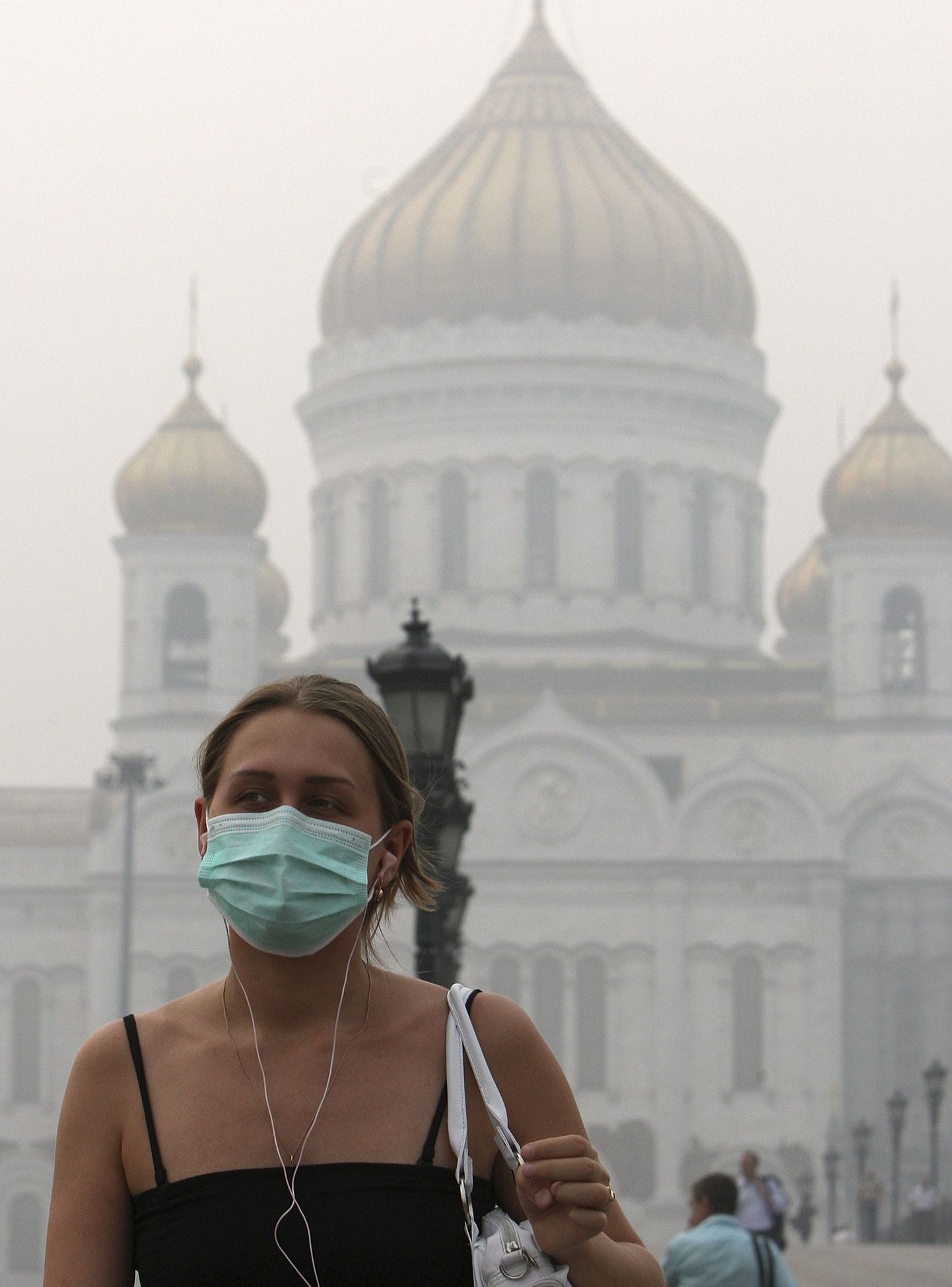 Maskiga naine suitsuses Moskvas. Taga paistab Lunastaja Kristuse katedraal.