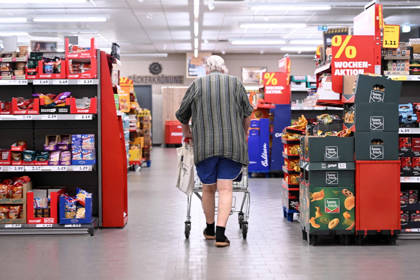 Пожилой мужчина с тележкой для покупок в продуктовом магазине Penny в Берлине 1 августа 2023 года.