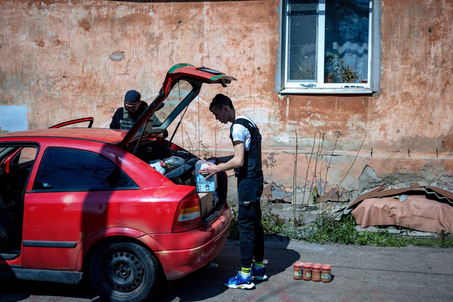 Kolm vabatahtlikku toimetamas oma punase Opeliga Harkivi inimestele toiduabi.