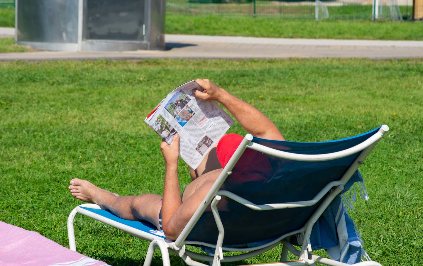 Inimene ajalehte lugemas ja sooja ilma nautimas