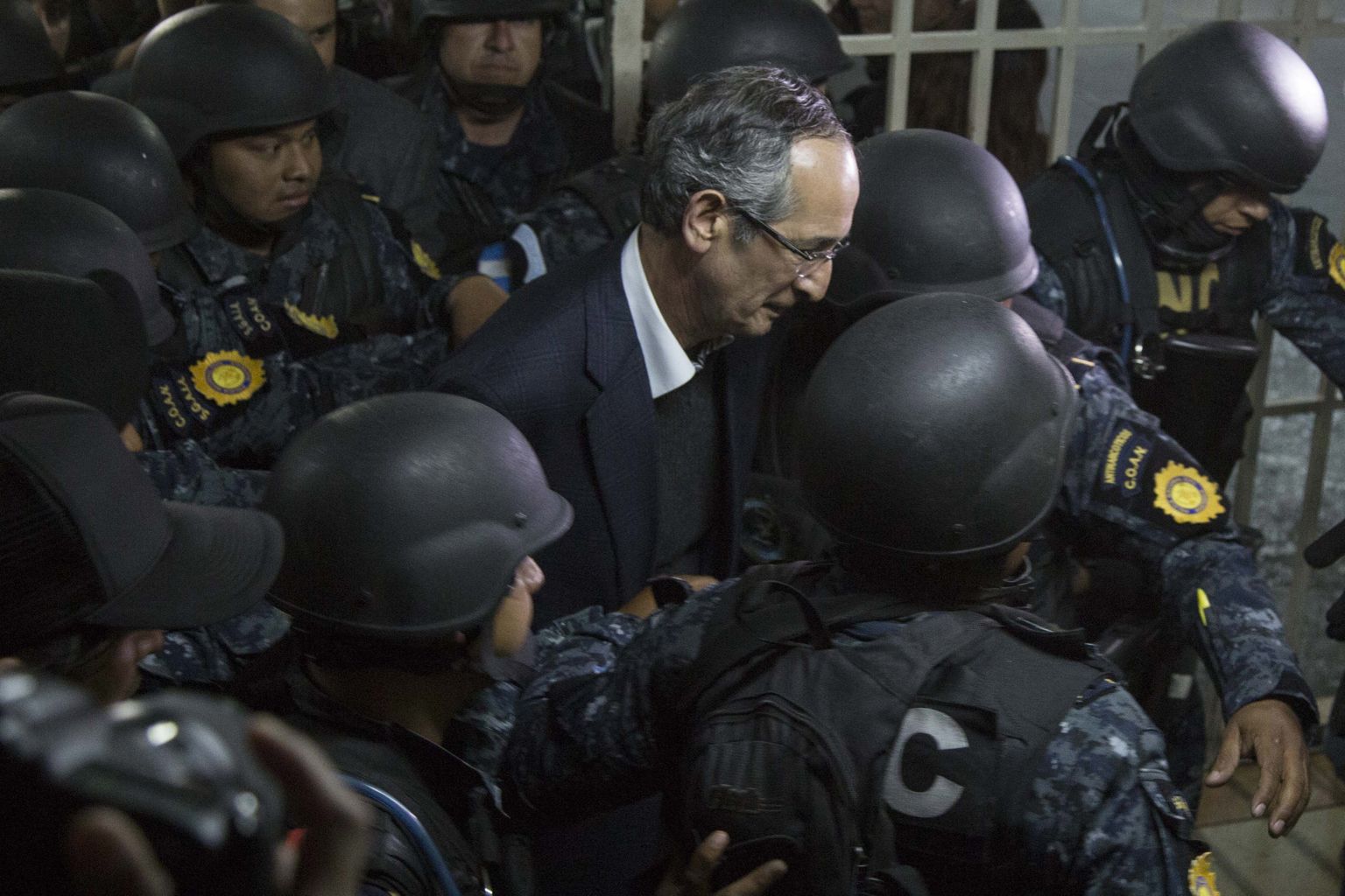 Guatemala ekspresident Alvaro Colom toimetatakse politseinike saatel kohtusse.