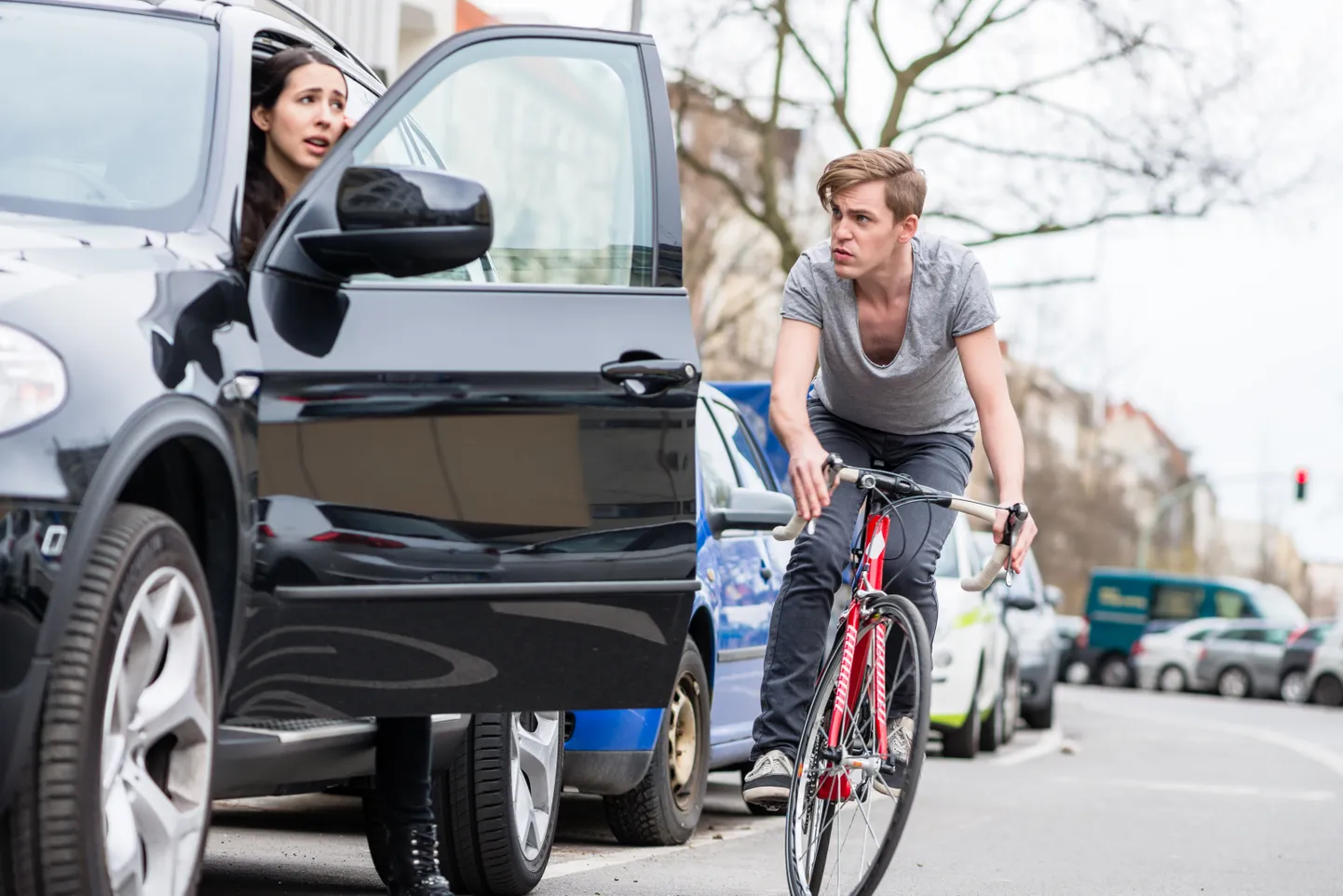 Automašīna ar atvērtām durvīm un velosipēdists