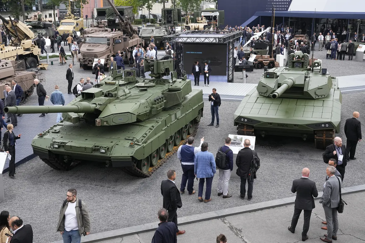 Visitors gather by a Leopard 2 A8 tank, left, and a Leopard 2A-RC-3.0 tank at the Eurosatory Defense and Security exhibition of 2024 in Villepinte, north of Paris.