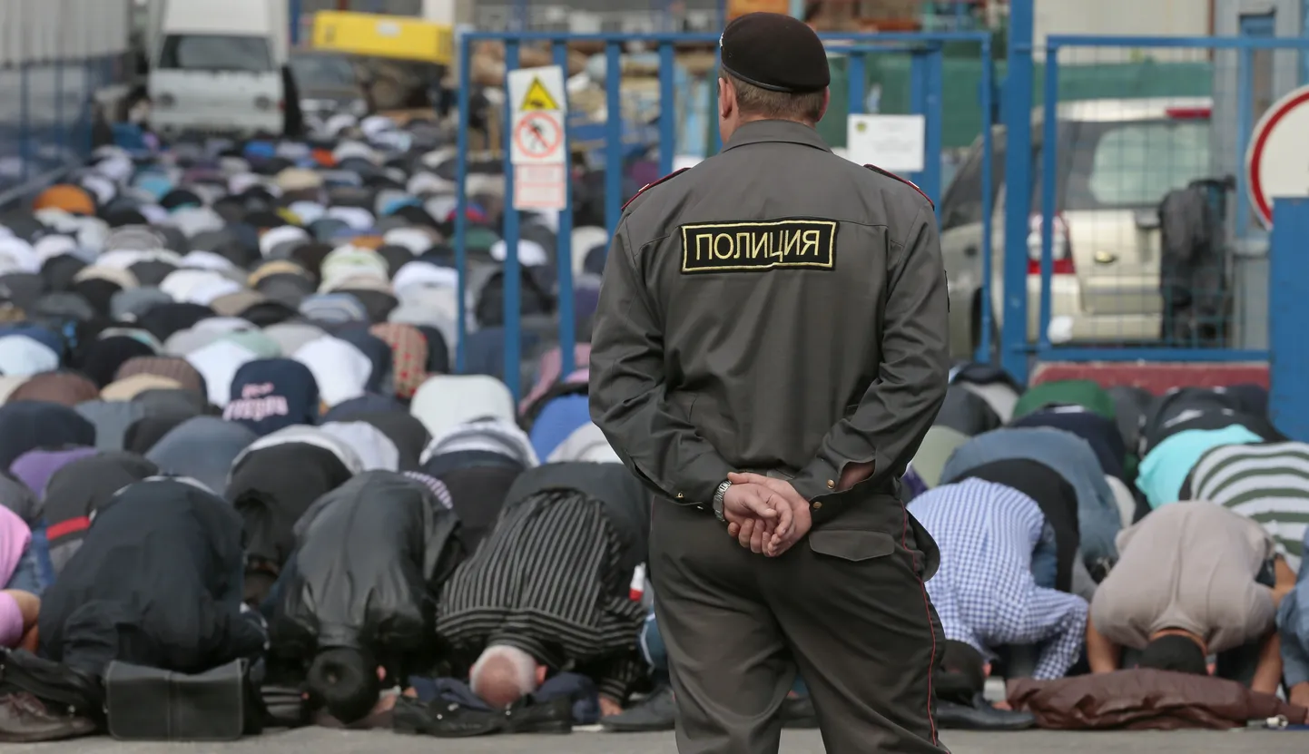 Vene politseinik palvetavaid moslemeid valvamas.