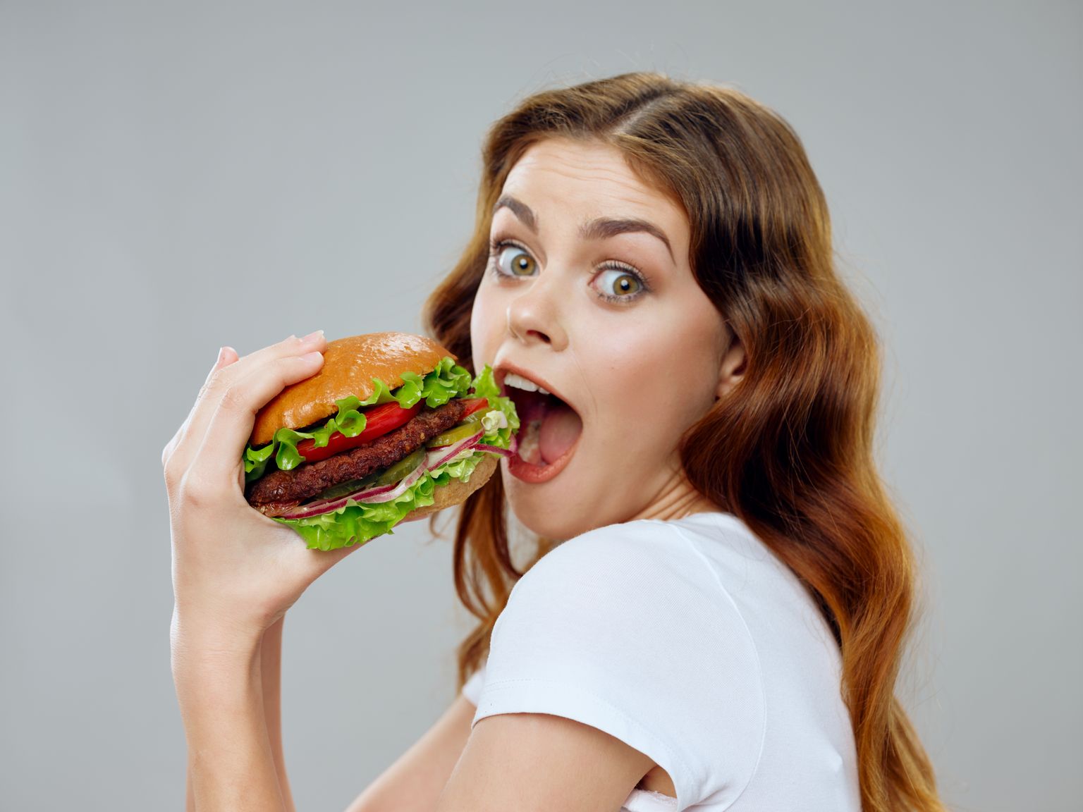 Женщина ест бургер. Иллюстративное фото